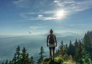 Person standing on mountain peak at sunrise, symbolizing a purposeful journey.